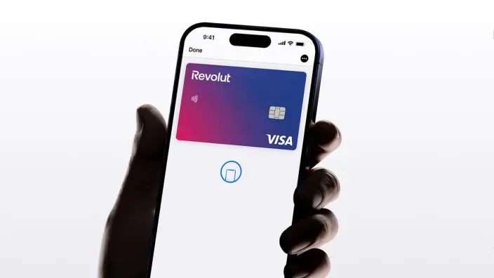 Mano sosteniendo un smartphone que muestra una tarjeta virtual de Revolut.