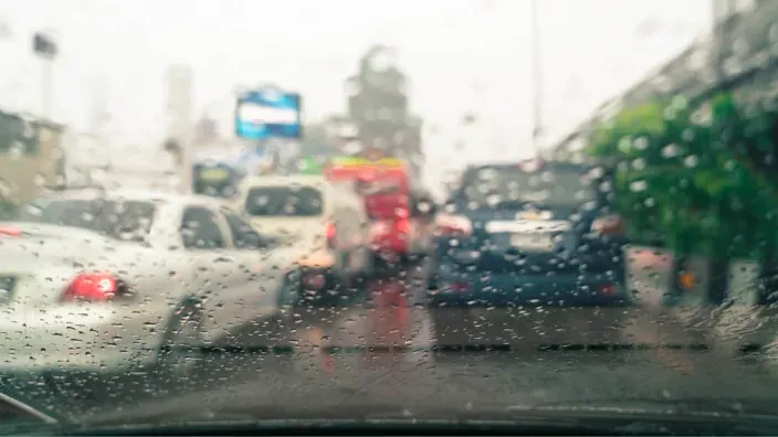 Vista a través del parabrisas de un coche bajo la lluvia, simbolizando la importancia de la visibilidad y seguridad vial.