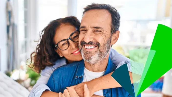 Primer plano de una pareja de mediana edad sonriendo y abrazada, con una superposición gráfica de la identidad visual de Unicaja
