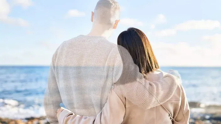 Pareja abrazada frente al mar para representar la paz mental y seguridad que aporta un buen seguro de decesos.