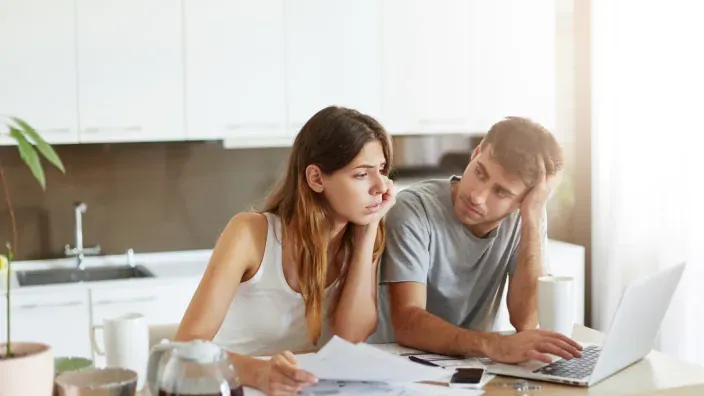 Pareja preocupada revisando sus finanzas y facturas en casa.