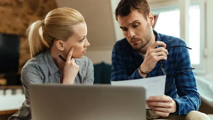 Pareja preocupada revisando facturas o un contrato.