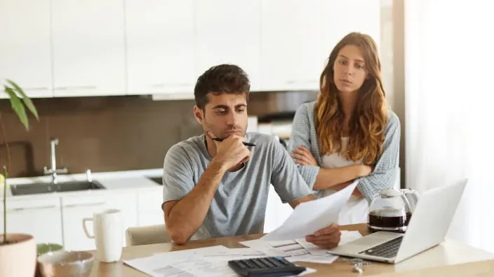 Pareja joven preocupada revisando las finanzas del hogar.