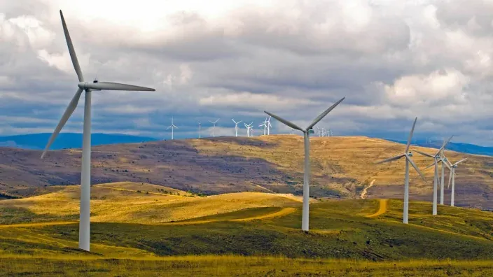 Parque eólico en entorno verde y montañoso.