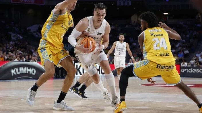 Jugador del Real Madrid intenta penetrar entre dos defensores del Gran Canaria durante un partido de la Liga Endesa.