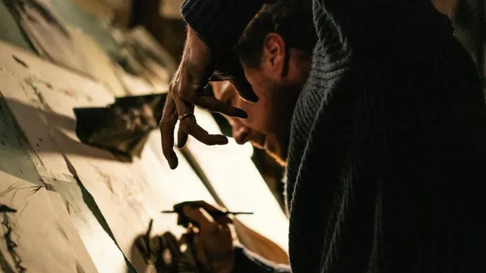 Un hombre realiza un ritual dibujando símbolos en una escena del drama psicológico Esa con alas