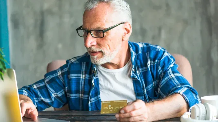 Hombre mayor realizando una compra online segura con su tarjeta.