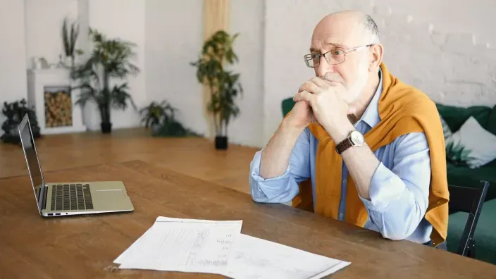 Hombre mayor preocupado revisando sus finanzas o la pensión.