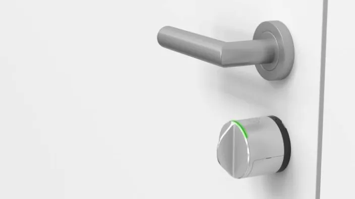 Cerradura inteligente plateada instalada en puerta blanca como medida moderna de seguridad para el hogar