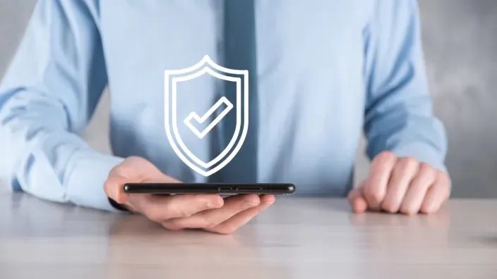 Persona sosteniendo un móvil con un icono de escudo de seguridad digital sobre la imagen