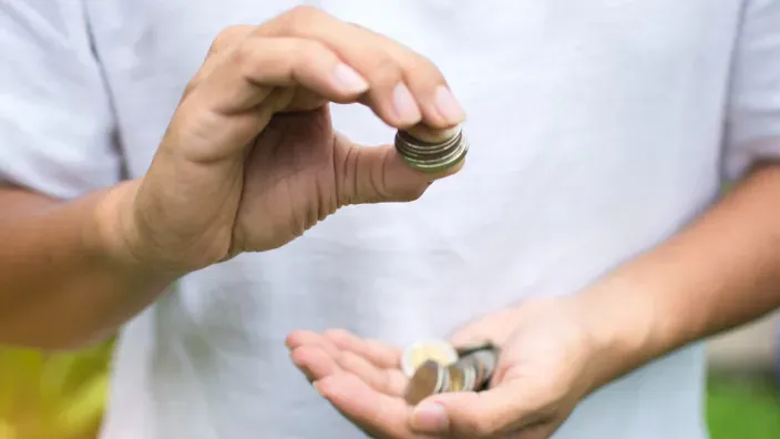 Manos sosteniendo pila de monedas.