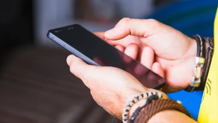 Primer plano de una persona sosteniendo un teléfono móvil con ambas manos, simbolizando comunicación y conexión digital.