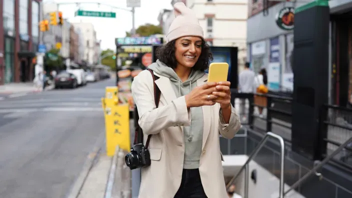 Mujer turista usando el móvil en una calle de Nueva York para consultar el mapa.