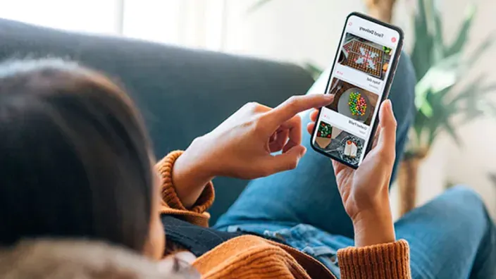 Mujer relajada en un sofá viendo suscripciones premium en su smartphone.