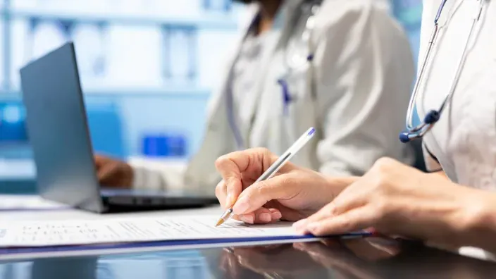 Personal médico rellenando informes y gestionando el historial clínico de un paciente.