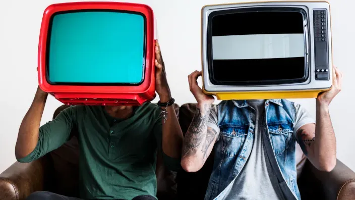 Dos personas con televisores retro en la cabeza.