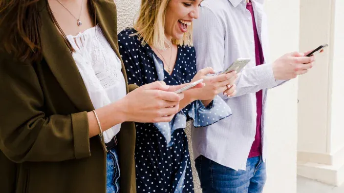 Grupo de jóvenes sonriendo y usando sus smartphones.