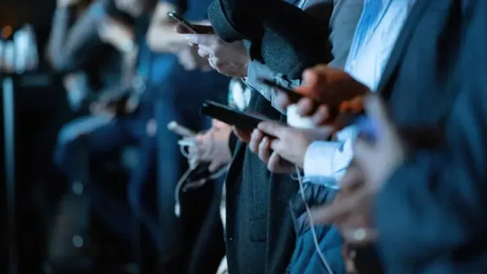 Fila de personas conectadas a sus smartphones, símbolo de la sociedad digital y la comunicación móvil.
