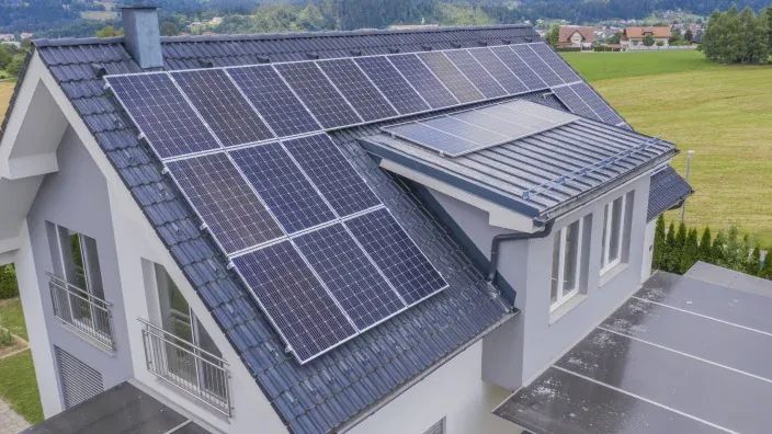 Casa de campo con el tejado gris y llena de placas solares fotovoltaicas para autoconsumo.