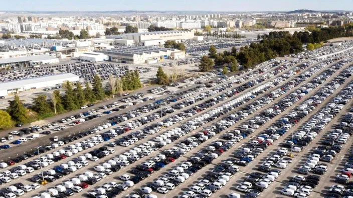 Vista aérea de un gran aparcamiento lleno de coches nuevos en una planta de automóviles.