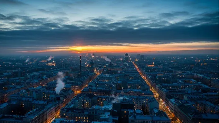 Imagen general de una ciudad a primeras horas del día, con el sol saliendo y las luces encendidas.