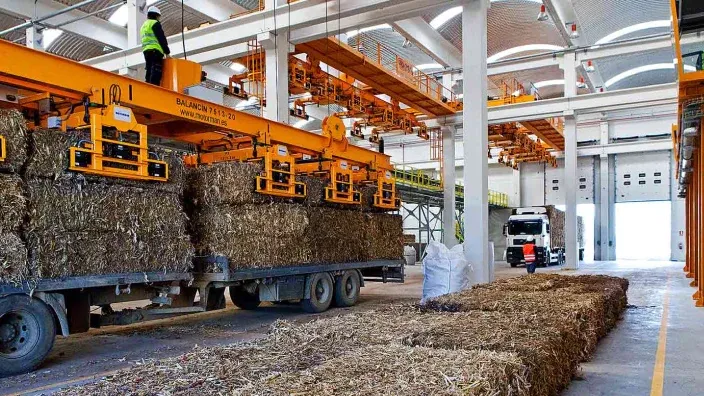 Instalaciones industriales de una planta de biomasa con maquinaria y pacas de materia orgánica.