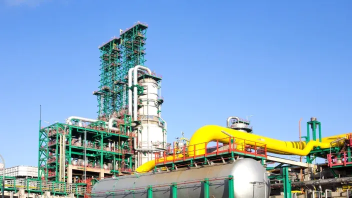 Planta industrial con tuberías amarillas y estructuras metálicas en complejo petroquímico o de gas.