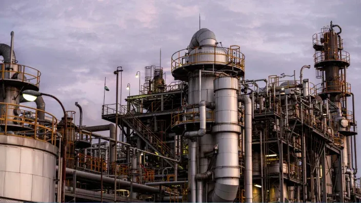 Planta industrial de refino con torres y tuberías al atardecer