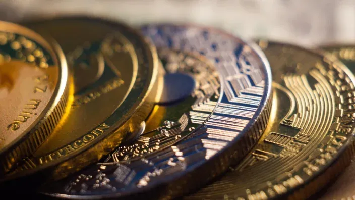 Primer plano de varias monedas físicas de criptomonedas, representando la inversión en activos digitales.