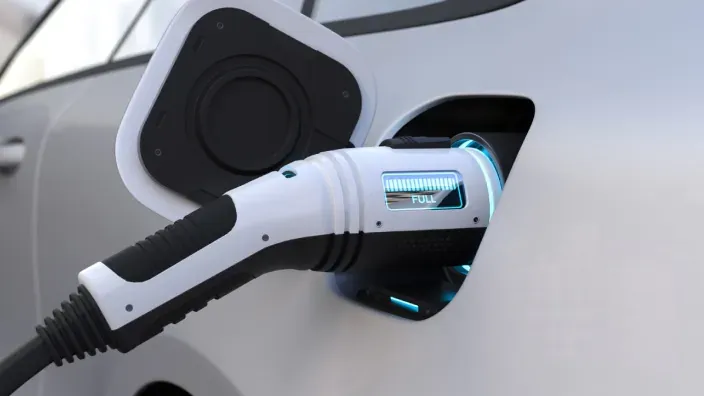 Primer plano de un conector enchufado a un coche eléctrico durante la carga.