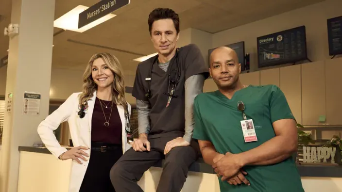 Los tres protagonistas de la serie Scrubs posando sobre el mostrador de un hospital