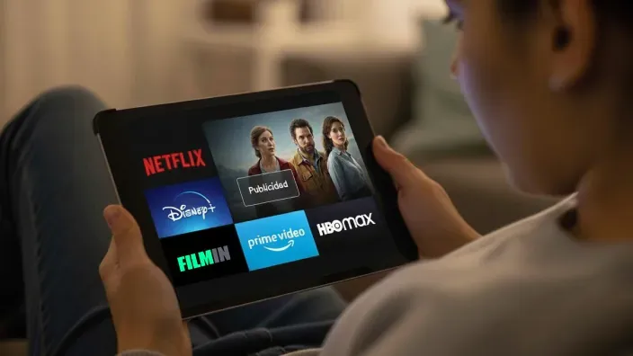 Mujer ve publicidad en una tablet con las apps de Netflix, Disney+ y HBO Max.