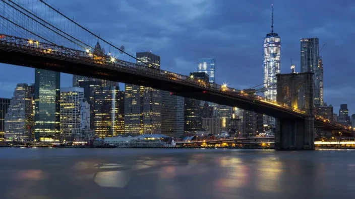 Puente de Brooklyn con el skyline de Nueva York iluminado al anochecer.