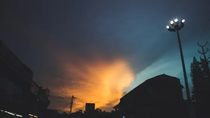 Puesta de sol en la ciudad con farolas encendidas.