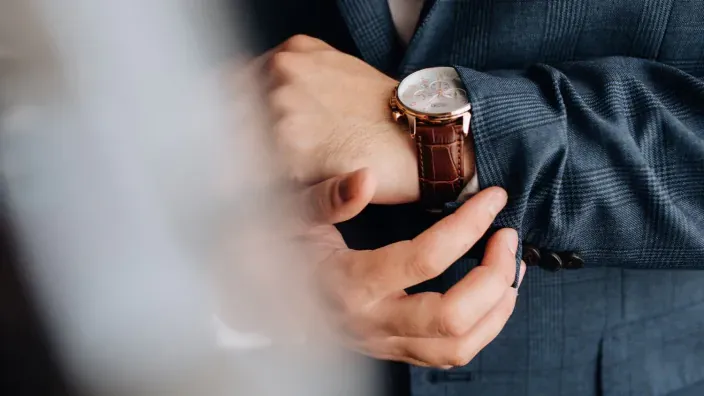 Hombre con traje de chaqueta ajustando su reloj de pulsera de lujo.