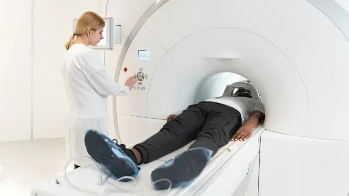 Técnico sanitario realizando una prueba de resonancia magnética (RM) a un paciente en un hospital.