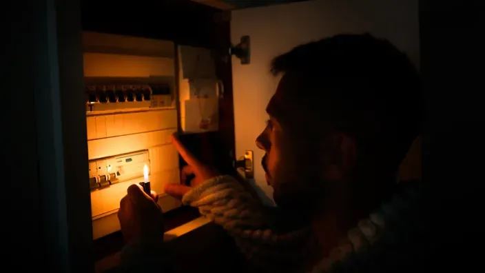 Persona revisando el cuadro eléctrico de su vivienda durante un corte de luz.