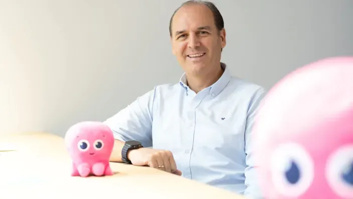 Roberto Giner, CEO de Octopus Energy España, sentado junto a la mascota de la compañía en forma de pulpo rosa.