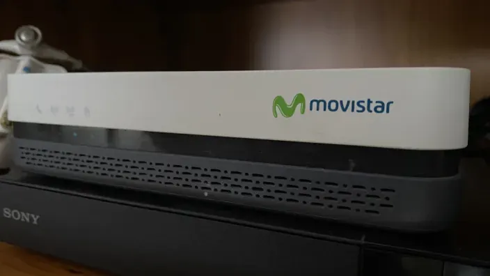 Router de Movistar encendido sobre un muebley otro dispositivo de la marca Sony.