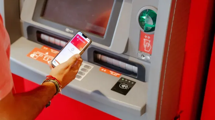 Cliente utilizando el móvil para retirar dinero en un cajero del Banco Santander
