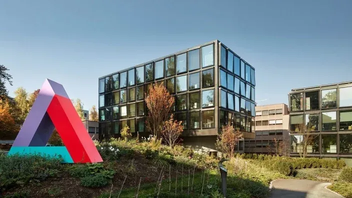 Edificio corporativo de Helvetia Seguros, una moderna construcción de cristal con un logo tridimensional de colores en el exterior.