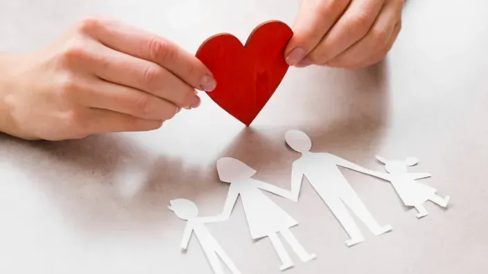 Concepto de seguro de vida y protección familiar con un corazón sobre siluetas de papel.