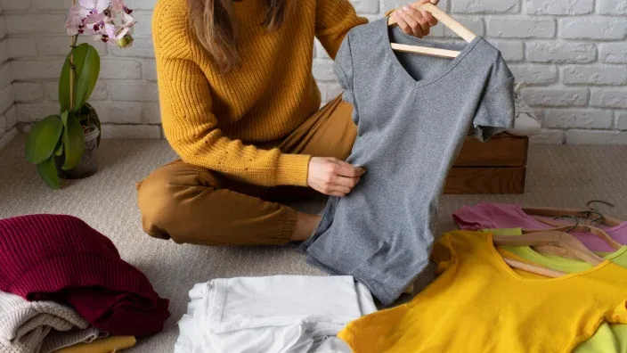 Persona seleccionando y organizando ropa de segunda mano para venderla online.
