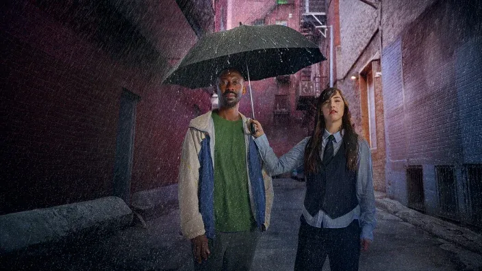 Hombre y mujer en un callejón bajo la lluvia con un paraguas para representar una escena de la serie Empatía.