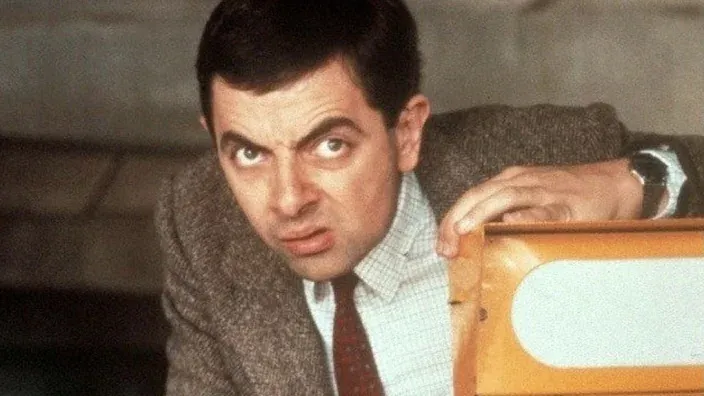 Mr. Bean (Rowan Atkinson) con su icónica expresión de humor y sospecha, en una escena de la clásica comedia británica.