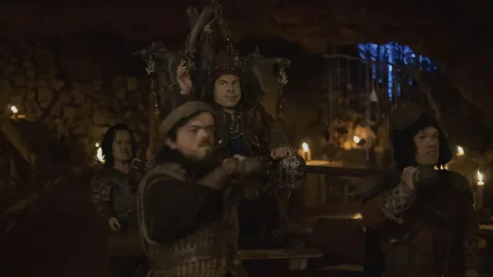 Warwick Davis como Willow Ufgood en la serie de fantasía Willow, en una escena en una cueva con otros personajes.