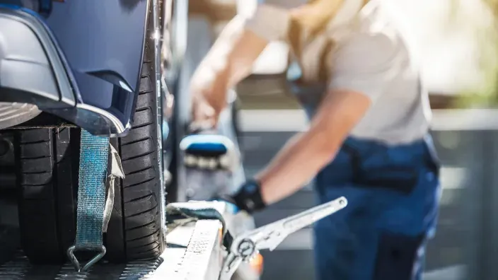 Operario asegurando un coche en una grúa durante una asistencia en carretera.