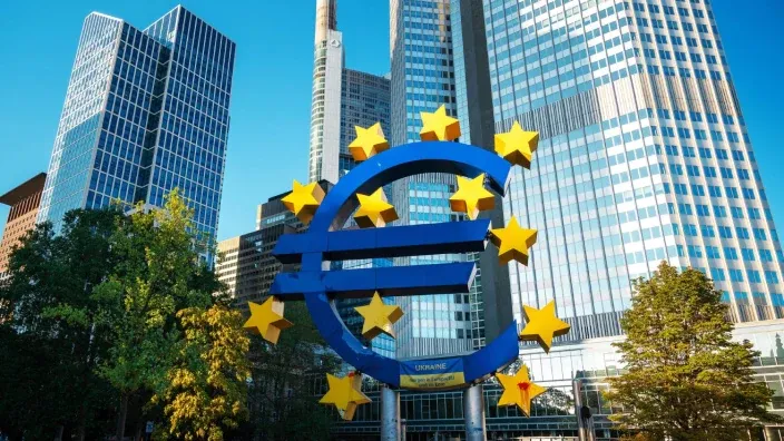 Escultura del euro en Fráncfort frente a rascacielos, símbolo del Banco Central Europeo y la economía de la eurozona.