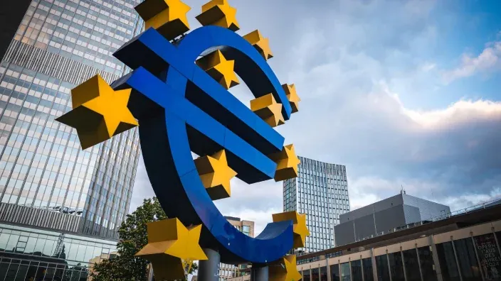 Escultura del simbolo del euro frente a edificios financieros de la zona euro.