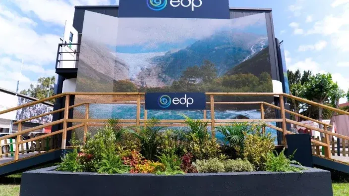 Stand de EDP con una gran pantalla, barandillas de madera y jardineras en la parte frontal
